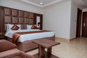 - une chambre avec un grand lit et un canapé dans l'établissement Fabino by Top Rank Hotels, à Abuja