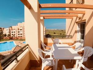 balcón con mesa, sillas y piscina en Las Garzas, Isla Canela - By AC REAL, en Isla Canela