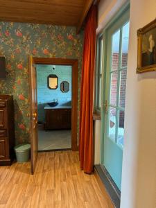 a bathroom with a sink and a mirror and a door at Vino Grando 't Klooster in Odiliapeel