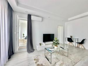 - un salon blanc avec une télévision et une table dans l'établissement Double Studio A601 StayInn by Cosmopolis, à Ştefăneştii de Jos