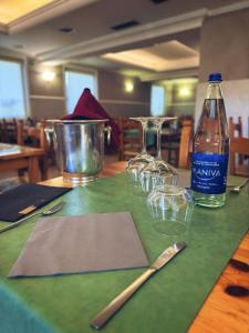 una mesa con copas de vino y una botella de agua en Albergo Trattoria Friulana AL TAJ, en Sevegliano