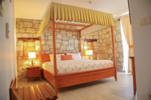 1 dormitorio con cama con dosel y pared de piedra en Alacatı Leylak Hotel, en Alacati