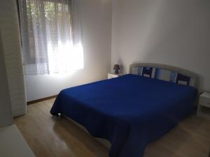 a blue bed in a white room with a window at Hiša Belin in Podbela