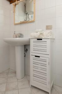 Un baño blanco con lavabo y espejo. en Raffinata taverna con camino, en Cala Liberotto