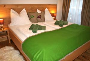 a large bed with green blankets and pillows on it at Appartementhaus Reiter in Altenmarkt im Pongau