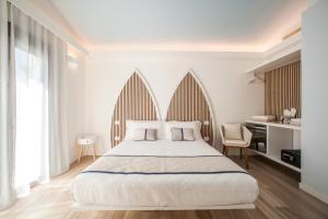 a white bedroom with a large bed and a chair at New Barcavela in Santa Margherita di Pula