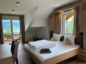 a bedroom with a bed and a table and a window at Gasthof Steinbichler in Nussdorf am Attersee
