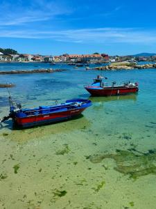 dos barcos sentados en el agua en la playa en Mar A Villa, en A Illa de Arousa 17 fotos más