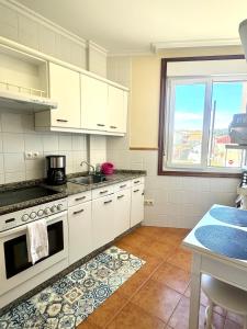 Una cocina con gabinetes blancos y un horno de estufa. en Mar A Villa, en A Illa de Arousa
