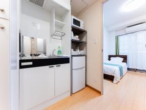 a kitchen with white cabinets and a bed in a room at Shinjuku/Shin-Okubo Sta 2min walk/Kabukicho 5 min in Tokyo