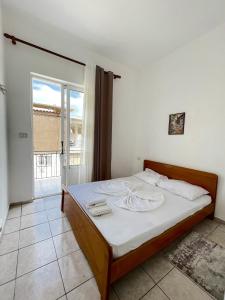 una camera da letto con un letto con lenzuola bianche e una finestra di Hostel Casa Mia SR a Sarandë