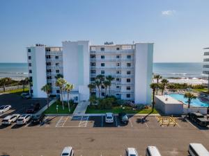 a large apartment building with a parking lot and the ocean at Shorehom by the Sea 46 in New Smyrna Beach