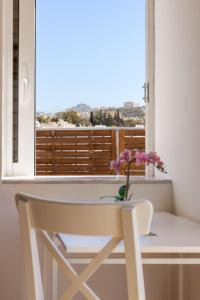 einen weißen Stuhl und einen Tisch mit einer Blumenvase in der Unterkunft The Terrace with Acropolis & Athens view in Athen