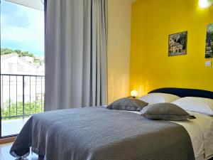 a bedroom with a bed with a yellow wall and a window at Apartments Casablanca in Podstrana