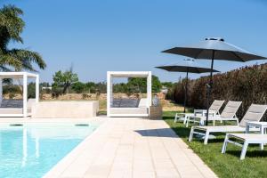 um grupo de cadeiras e um guarda-sol junto a uma piscina em Villa Lucia con piscina privata vicino al mare em Gallipoli