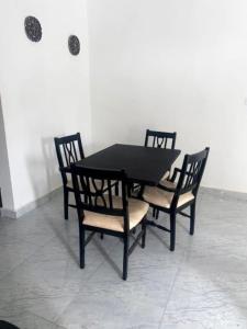a table and chairs with a black table and four chairs at 3 Bedroom Apartment in Brusubi in Jamisa