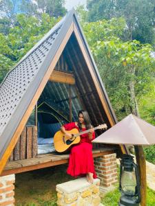 a woman in a red dress holding a guitar in front of a tiny house at Seattle Knuckles in Rangala