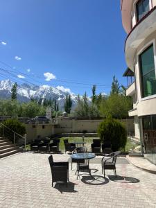 a patio with tables and chairs with mountains in the background at POLO LAND HOTEL Skardu in Tandal