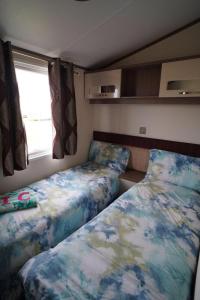 a small bedroom with a bed and a window at pets stay free 8 berth lux van heacham beach in Heacham
