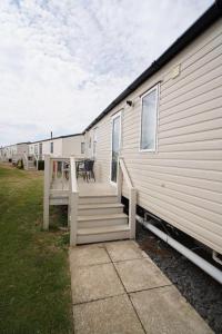 a house with a porch and stairs next to a building at pets stay free 8 berth lux van heacham beach in Heacham