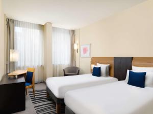 a hotel room with two beds and a desk at Novotel Budapest Danube in Budapest