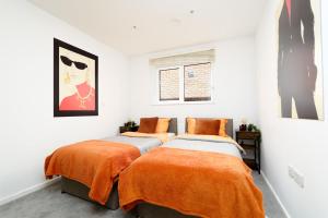 2 camas en una habitación blanca con sábanas de color naranja en Central Location, Sleeps 3, Perfect for Trades, en Hemel Hempstead