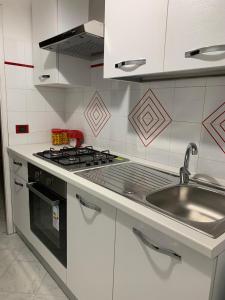 a white kitchen with a stove and a sink at Case La Spiaggia in Sciacca