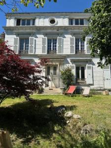 ein großes weißes Haus mit einer roten Bank davor in der Unterkunft Quai Sisley in Villeneuve-la-Garenne