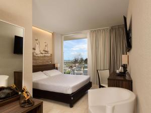 a hotel room with a bed and a balcony at Mercure Rimini Lungomare in Rimini