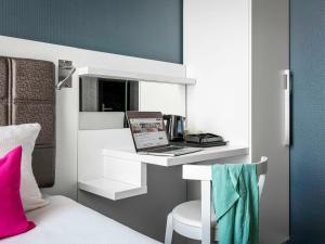 a room with a bed with a laptop on a shelf at ibis Styles Amsterdam Amstel in Amsterdam
