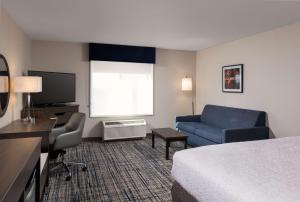 a hotel room with a bed and a couch and a television at Hampton Inn & Suites Manteca in Manteca