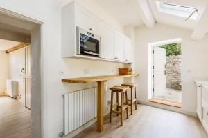 eine Küche mit einer Theke mit Hockern und einer Mikrowelle in der Unterkunft Honeysuckle Cottage in Wareham