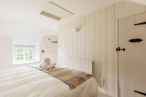 ein weißes Schlafzimmer mit einem Teddybär, der auf einem Bett sitzt in der Unterkunft Honeysuckle Cottage in Wareham