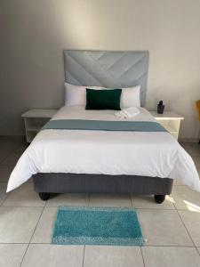 a bedroom with a large bed with a green pillow at Divine Guest Lodge in Rustenburg