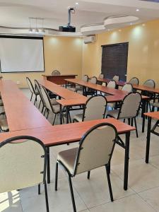 a classroom with wooden tables and chairs and a whiteboard at Divine Guest Lodge in Rustenburg