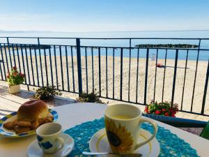 a table with two cups of coffee and a plate of food on the beach at Case La Spiaggia in Sciacca