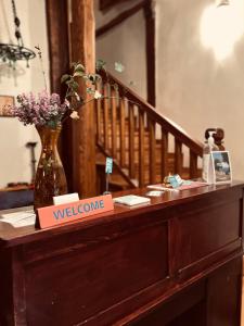 a welcome sign on a table with a vase of flowers at Aristotelous Alexandrou Historic Inn in Arnaia