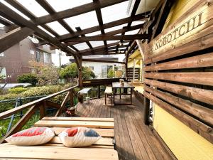 un balcón de madera con almohadas en una terraza de madera en Nobotchi のぼっち 5min walk to Noboribetsu st, en Noboribetsu