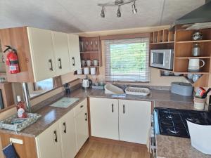 a kitchen with white cabinets and a counter top at Countryside Caravan Accommodation - Abergele in Abergele