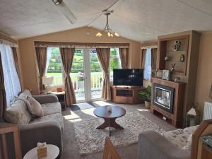 a living room with a couch and a tv at Countryside Caravan Accommodation - Abergele in Abergele