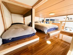 Duas camas num pequeno quarto com pisos em madeira em Nobotchi のぼっち 5min walk to Noboribetsu st em Noboribetsu