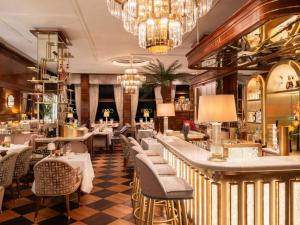 a restaurant with tables and chairs and a chandelier at Fairmont Hotel Vier Jahreszeiten in Hamburg