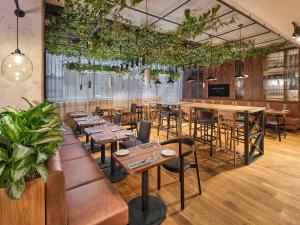 a restaurant with wooden tables and chairs and plants at Mercure Katowice Centrum in Katowice