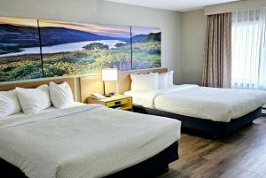a hotel room with two beds and a painting on the wall at Days Inn and Suites by Wyndham Downtown Missoula-University in Missoula