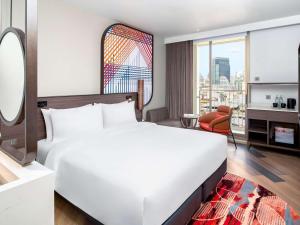 a bedroom with a large white bed and a living room at Mercure Bangkok Surawong in Bangkok
