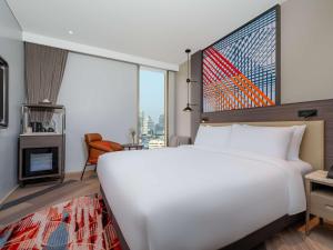 ein großes weißes Bett in einem Zimmer mit einem großen Fenster in der Unterkunft Mercure Bangkok Surawong in Bangkok