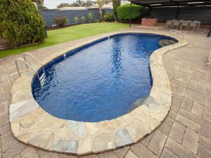 a swimming pool with a stone walkway around it at Breakfree Port Pirie in Port Pirie