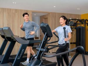 un hombre y una mujer en una cinta de correr en un gimnasio en Mercure Bangkok Surawong, en Bangkok