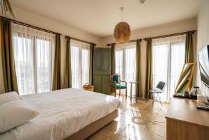 a bedroom with a large white bed and windows at CasaLyma Ayvalık in Ayvalık