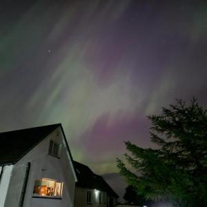 une maison avec des lumières dans une fenêtre la nuit dans l'établissement Balmoral Skye, à Portree